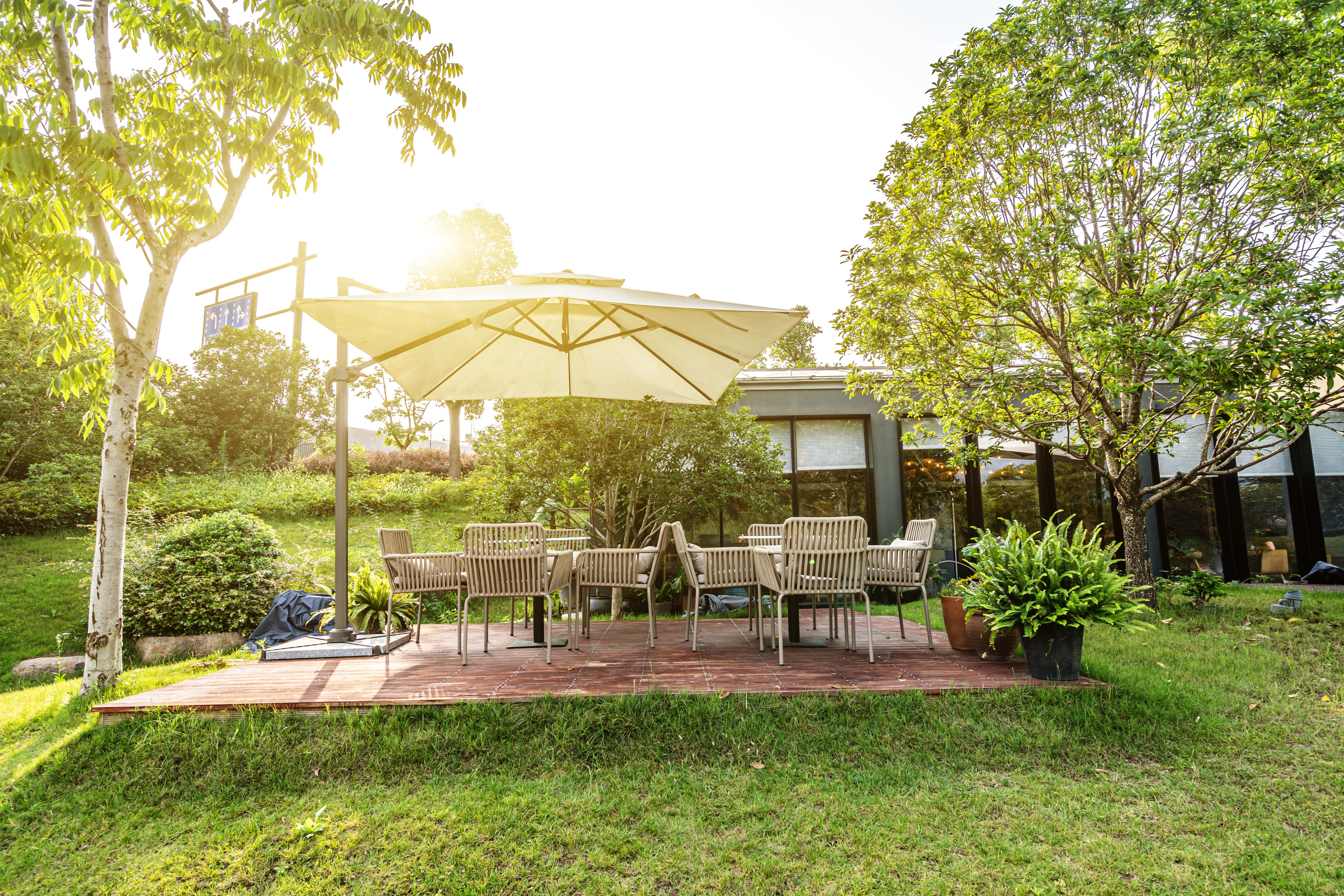 an image of a nicely landscaped yard with a patio full of table and chairs